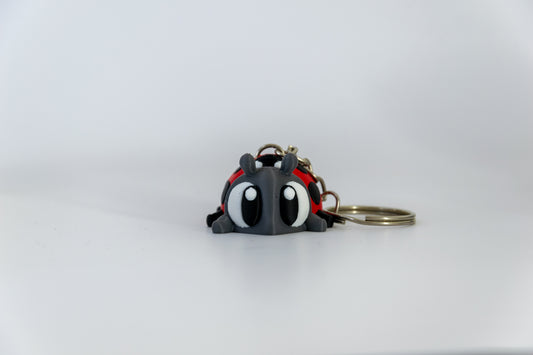 Porte-clés Coccinelle articulé MinoZoo rouge, gris foncé et noir, vue de face avec anneau sur fond blanc.