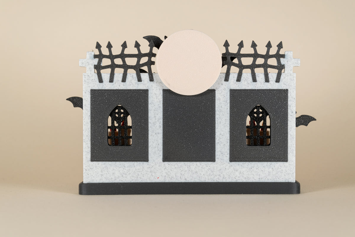 Dos du Repaire de Dracula MinoZoo, avec murs blancs et noirs, fenêtres gothiques et lune.