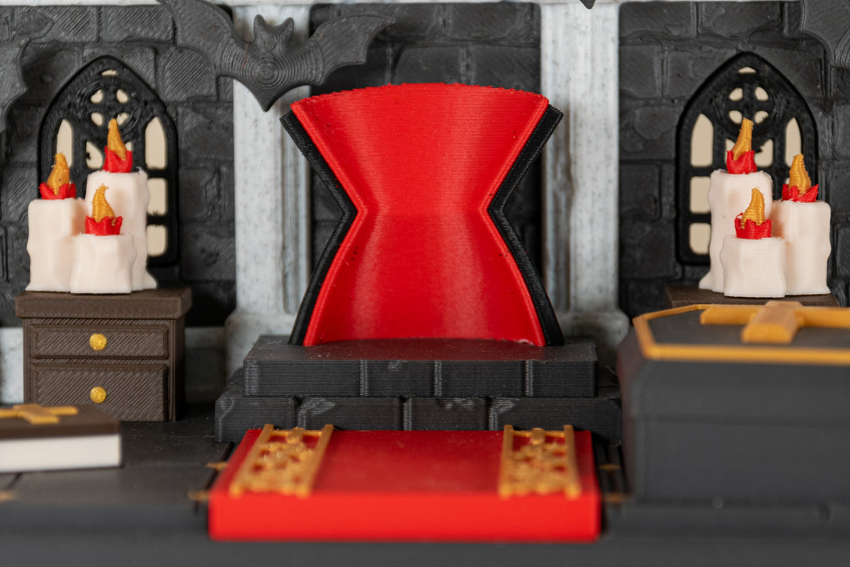 Détail du trône rouge du Repaire de Dracula MinoZoo, entre bougies et fenêtres gothiques.