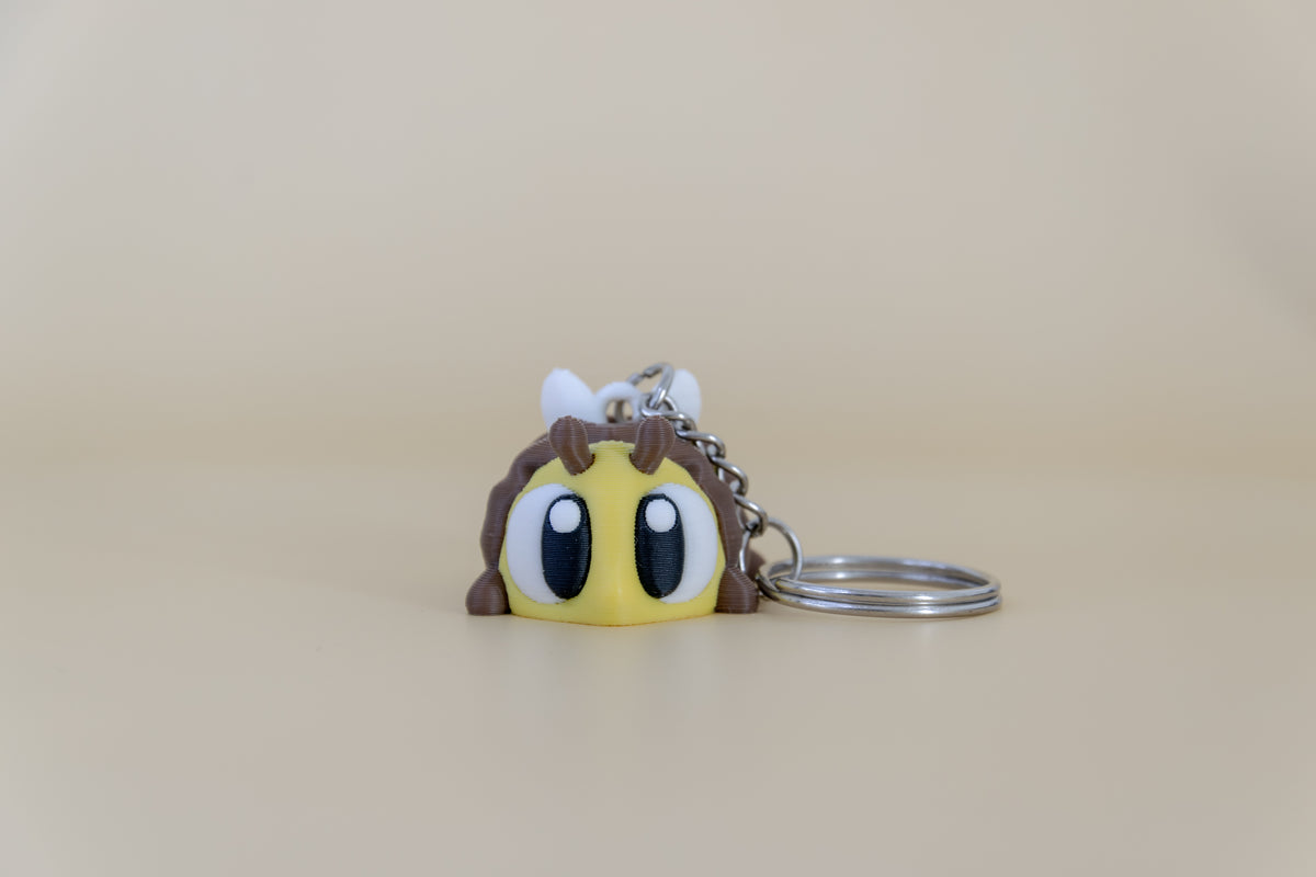 Porte-clés Abeille articulé MinoZoo jaune, brun et blanc, vue de face avec anneau sur fond beige.