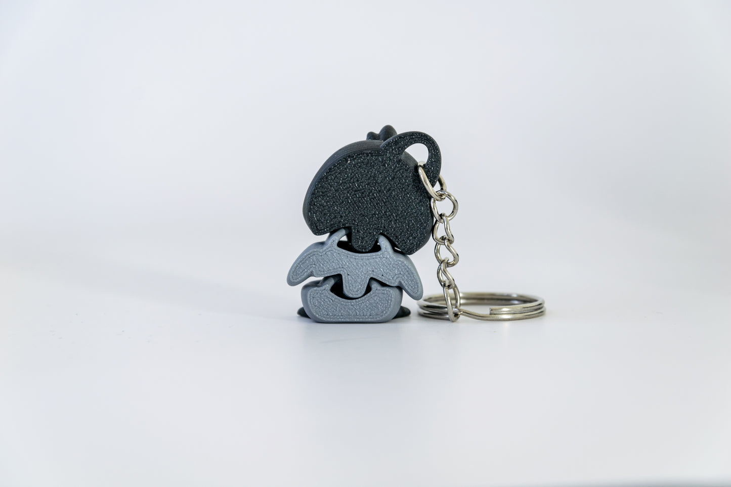 Porte-clés Bébé Pingouin articulé MinoZoo noir, blanc et gris moyen, vu de dos avec chaîne et anneau à droite.