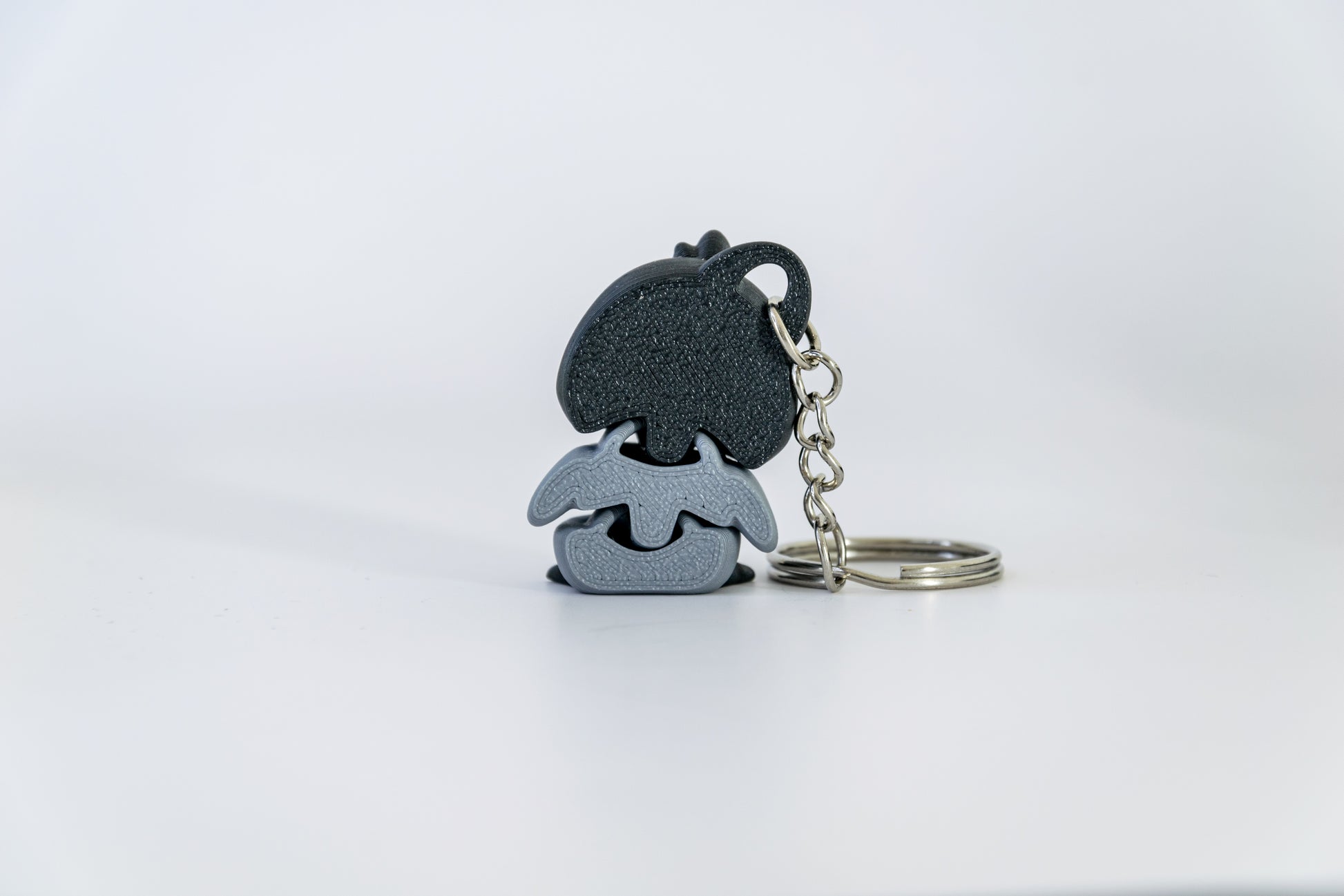 Porte-clés Bébé Pingouin articulé MinoZoo noir, blanc et gris moyen, vu de dos avec chaîne et anneau à droite.