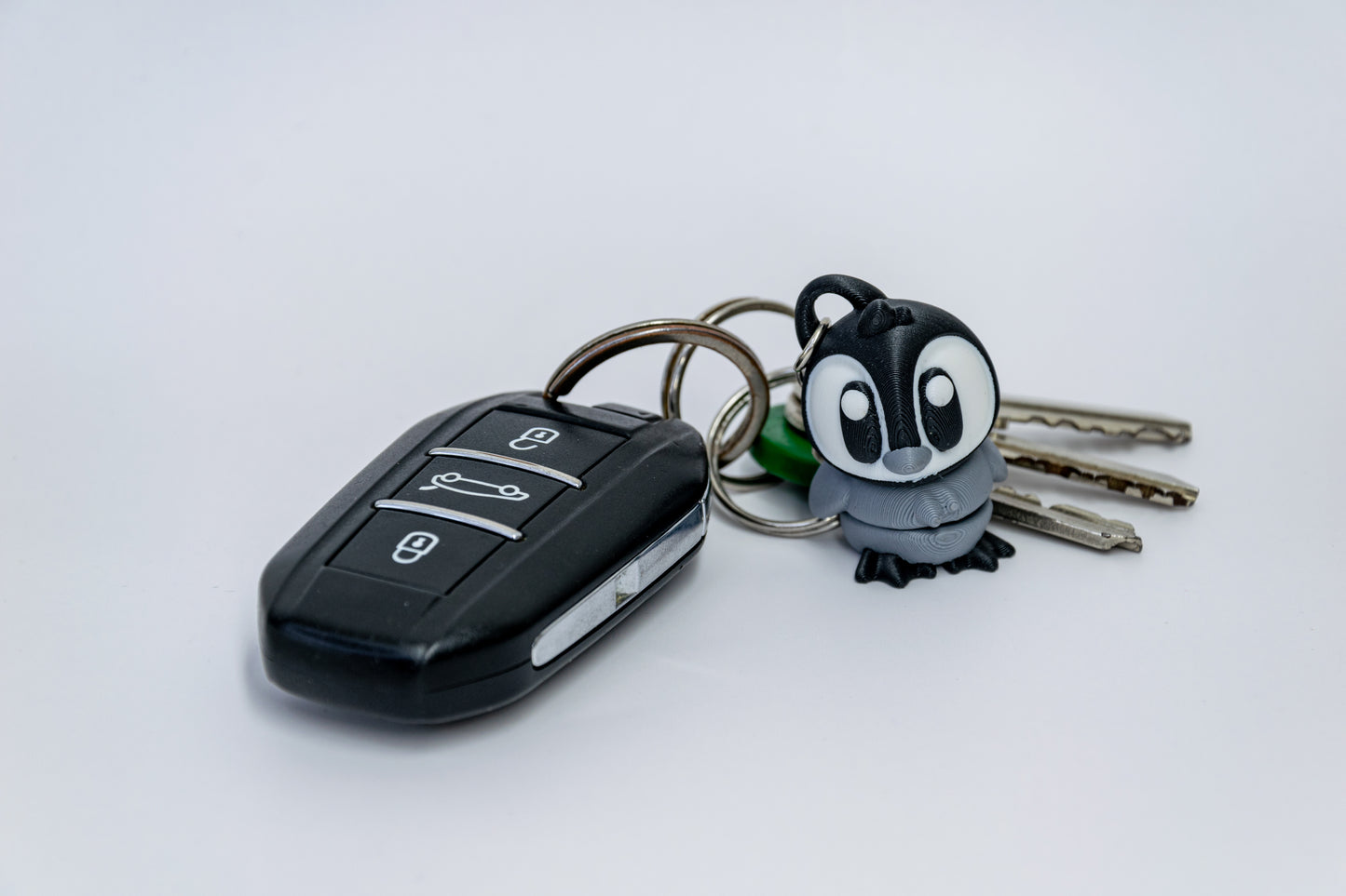 Porte-clés Bébé Pingouin articulé MinoZoo noir, blanc et gris moyen, de trois quarts avec des clés de voiture