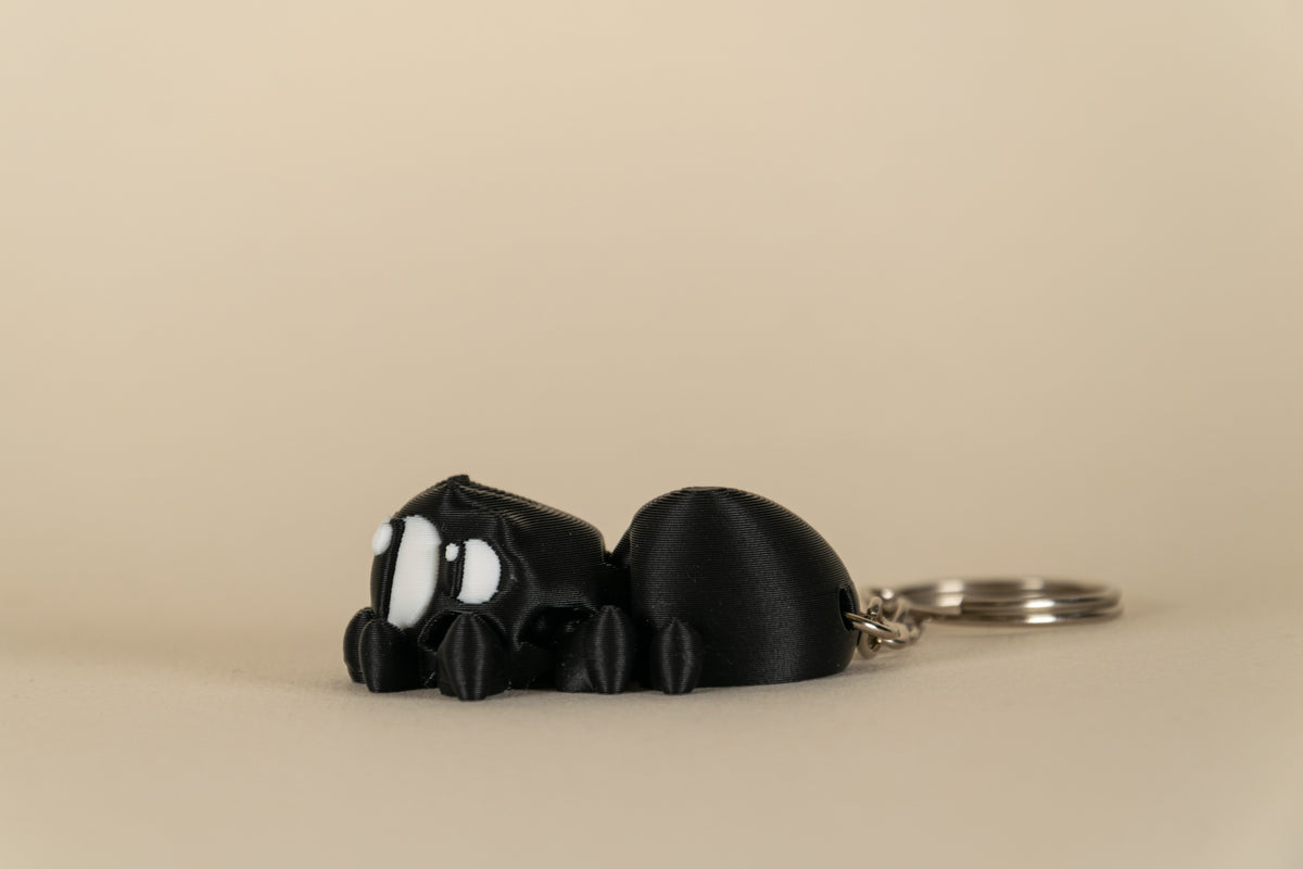 Porte-clés Black Spider articulé MinoZoo noir et blanc, vue de profil avec anneau métallique.