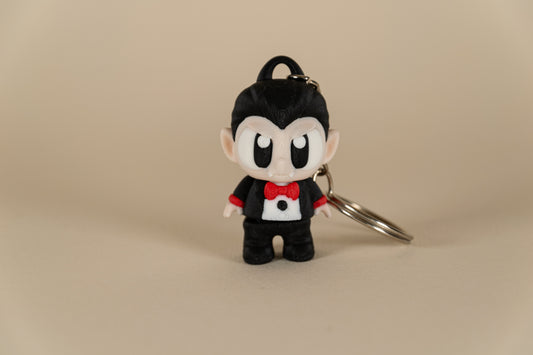 Porte-clés Dracula articulé MinoZoo noir, beige et rouge, vue de face sur fond beige.