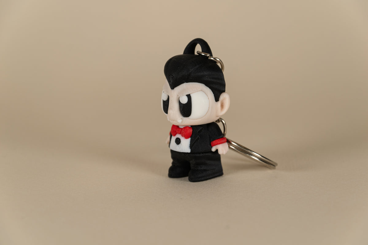 Porte-clés Dracula articulé MinoZoo noir, beige et rouge, vue trois-quarts sur fond beige.