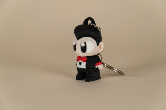 Porte-clés Dracula articulé MinoZoo noir, beige et rouge, vue trois-quarts sur fond beige.