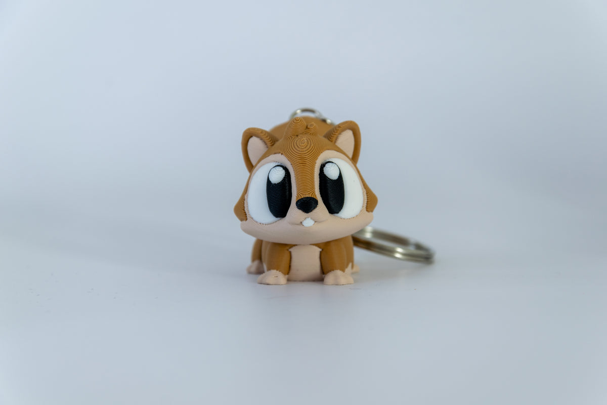 Porte-clés Écureuil articulé MinoZoo brun et brun clair, posé de face sur fond clair.