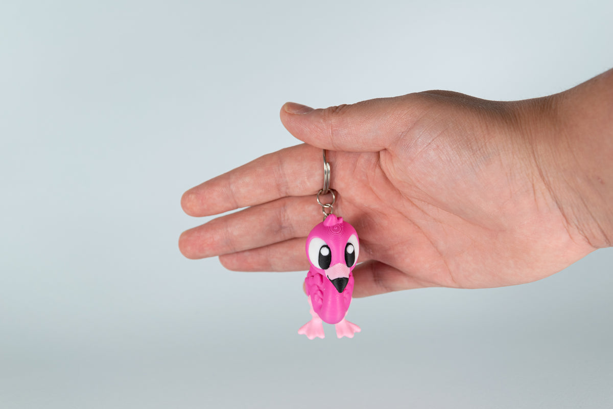 Porte-clés Flamant Rose articulé MinoZoo rose et rose clair, tenu de face dans une main.
