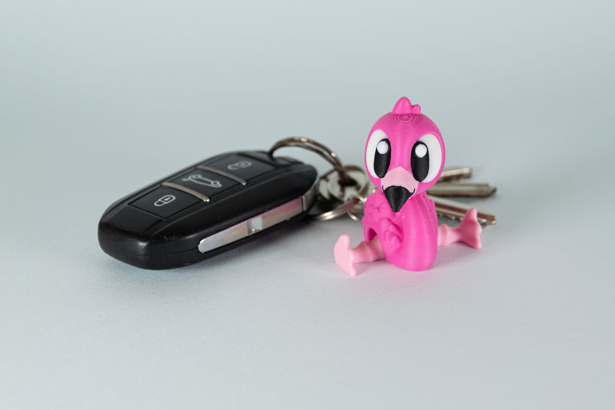 Porte-clés Flamant Rose articulé MinoZoo rose et rose clair, vue trois-quarts avec une clé de voiture.