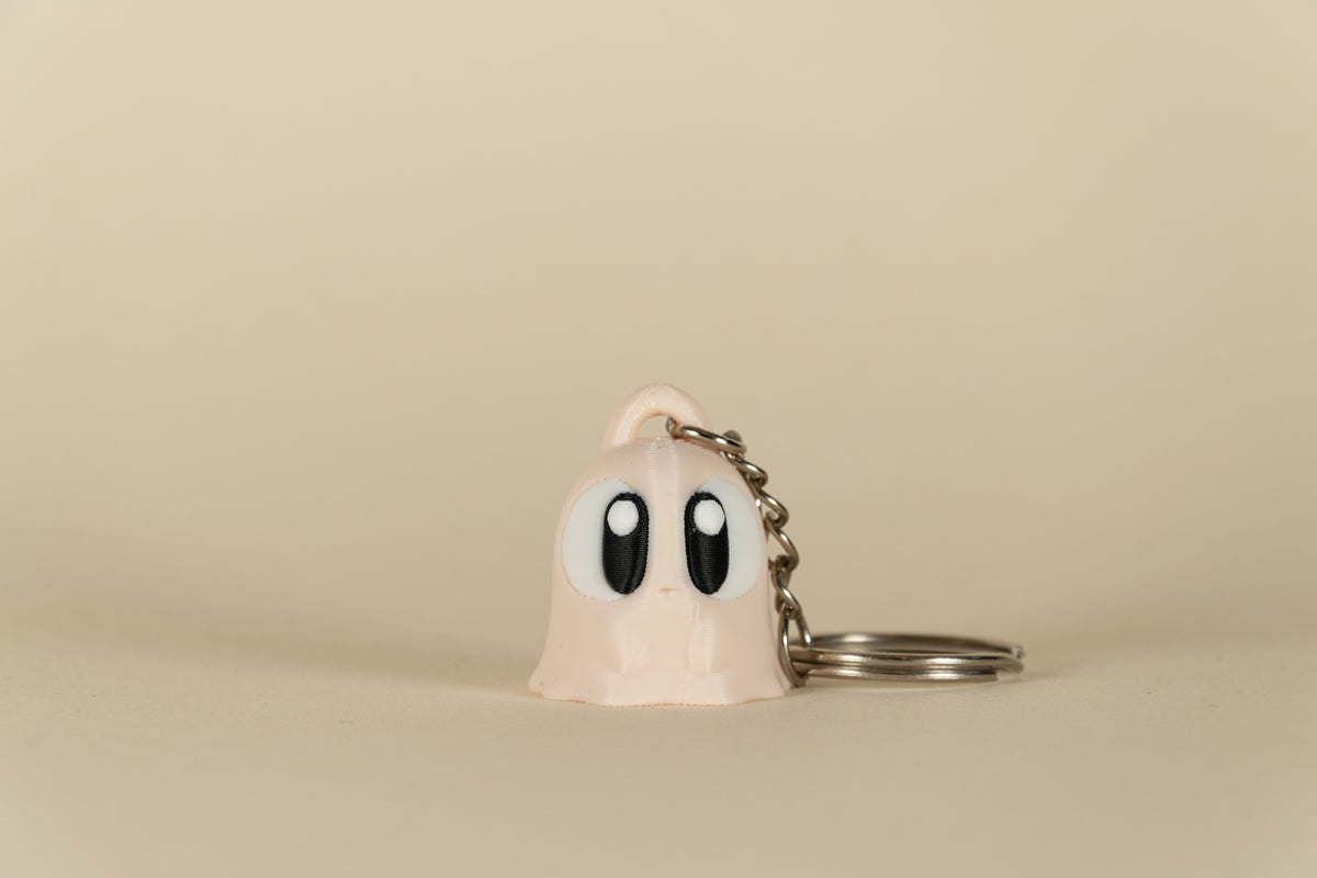 Porte-clés Ghost MinoZoo beige, noir et blanc, vue de face sur fond beige.