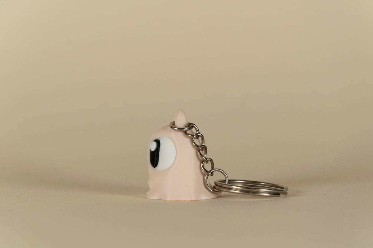 Porte-clés Ghost MinoZoo beige, noir et blanc, vue de profil avec chaîne et anneau.