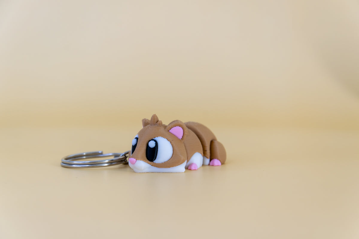 Porte-clés Hamster articulé MinoZoo brun et blanc, vue trois-quarts montrant son corps segmenté.