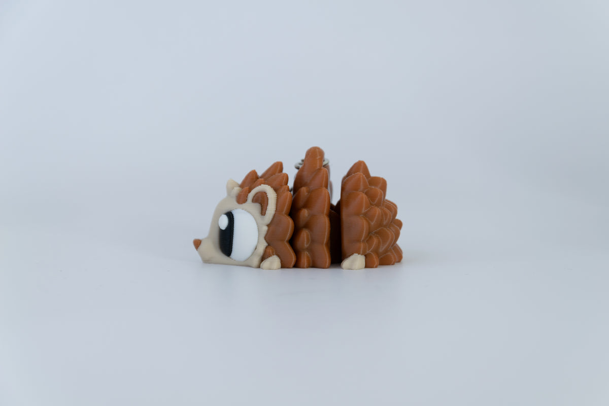 Porte-clés Hérisson articulé MinoZoo brun et beige, vue de profil avec les segments du corps articulé écartés.