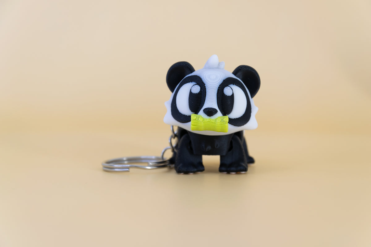 Porte-clés Panda Bambou articulé MinoZoo noir, blanc et vert, vue de face sur fond beige.