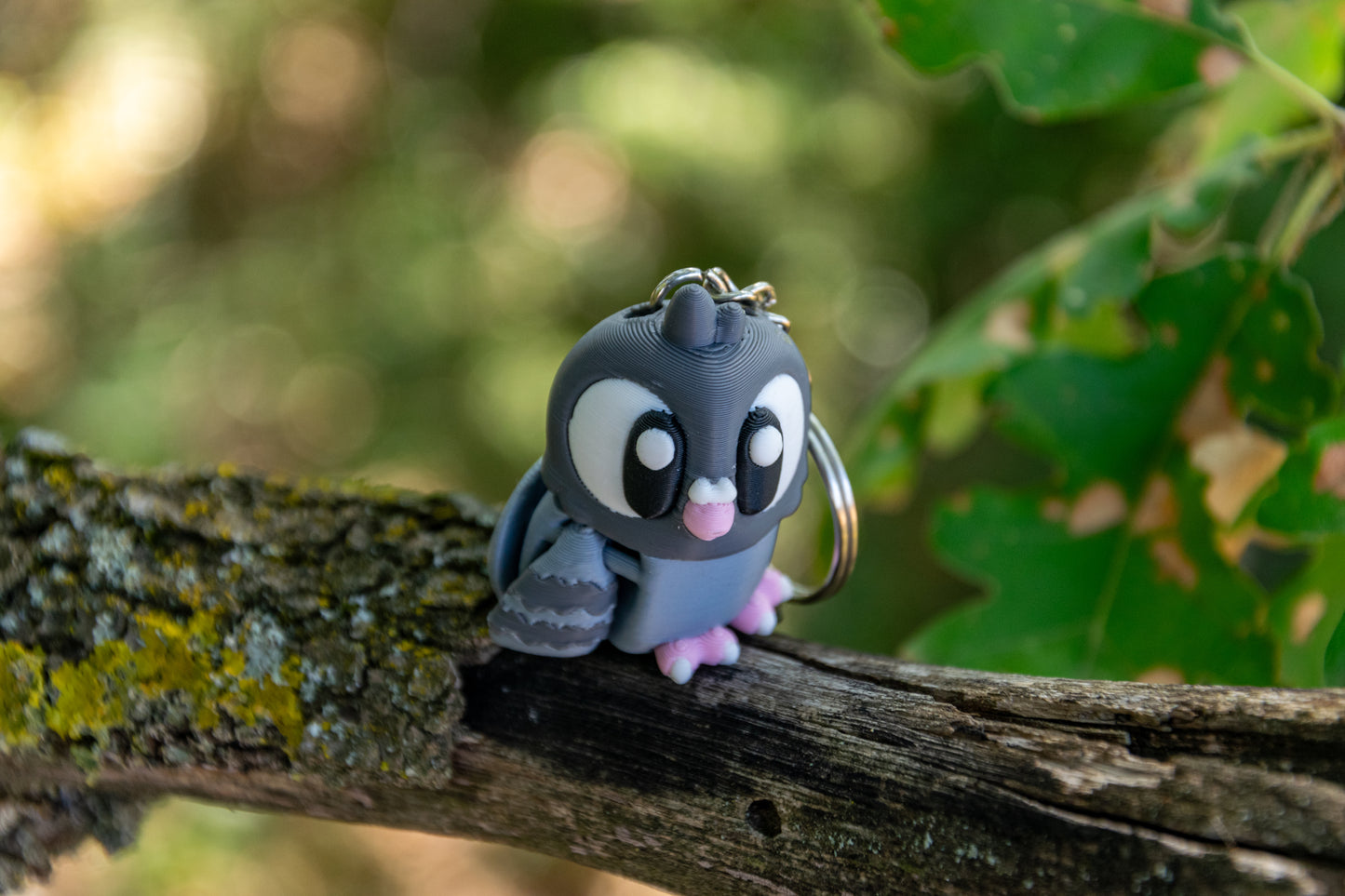 Porte-clés Pigeon articulé MinoZoo gris bleuté et rose Sakura, vu de trois quarts en légère plongée sur une branche.