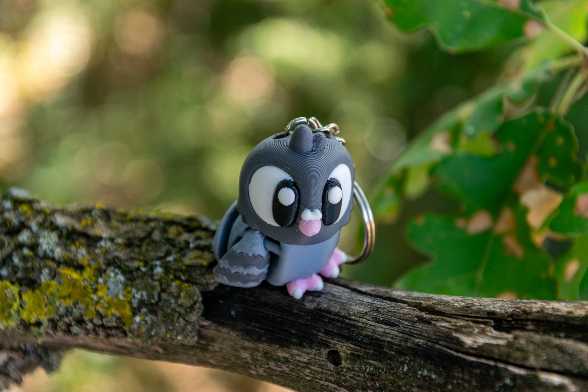 Porte-clés Pigeon articulé MinoZoo gris bleuté et rose Sakura, vu de trois quarts en légère plongée sur une branche.