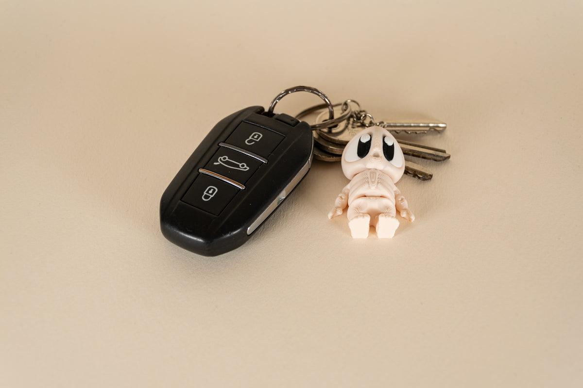 Porte-clés Skeleton articulé MinoZoo beige, noir et blanc, vue de dessus avec des clés de voiture.