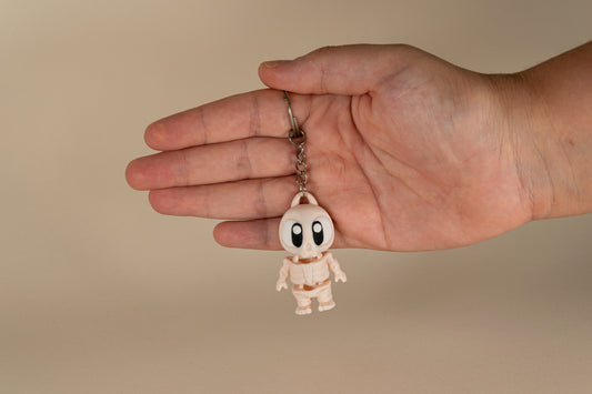 Porte-clés Skeleton articulé MinoZoo beige, noir et blanc, vue de face tenu dans une main.