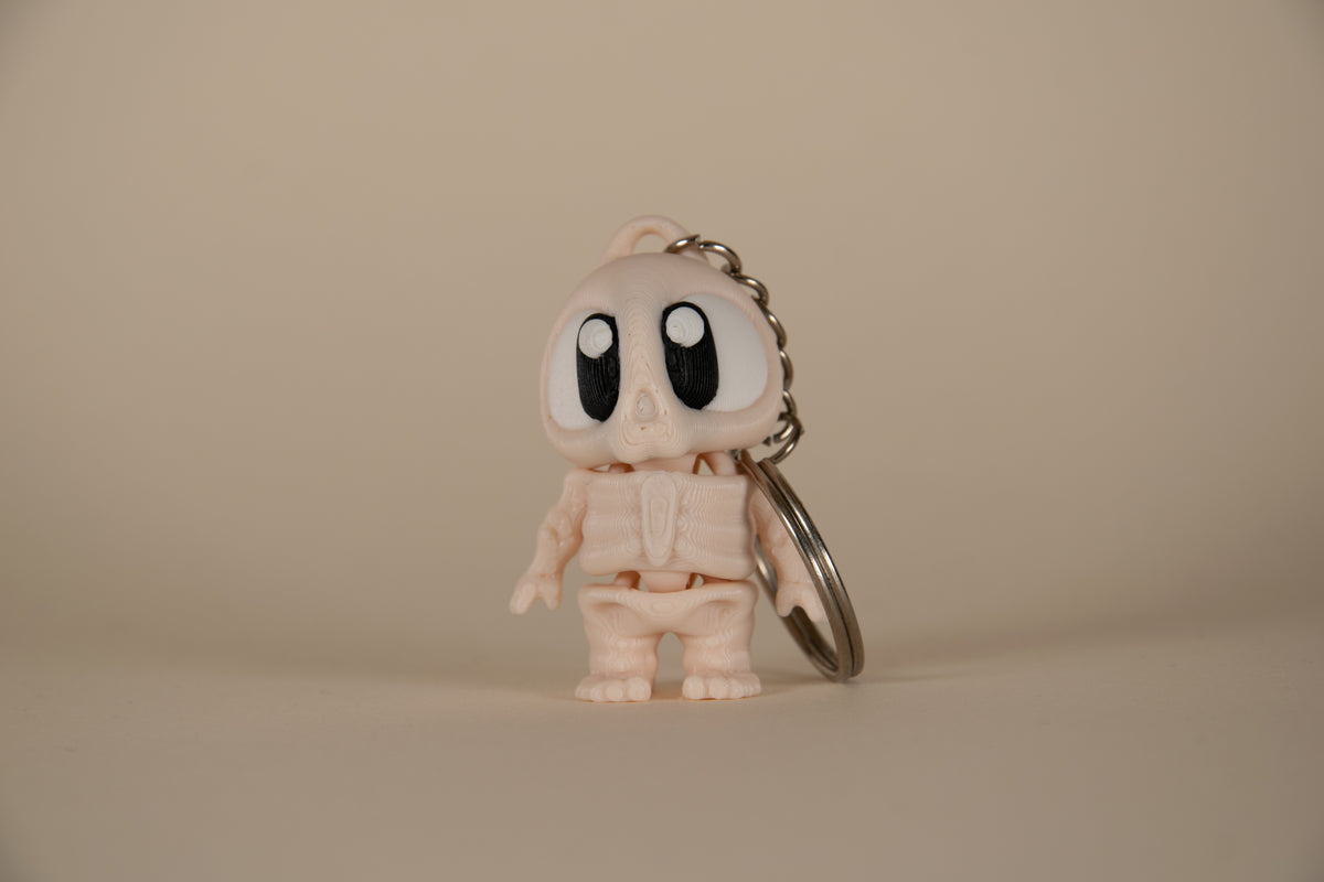 Porte-clés Skeleton articulé MinoZoo beige, noir et blanc, vue de face avec anneau métallique.