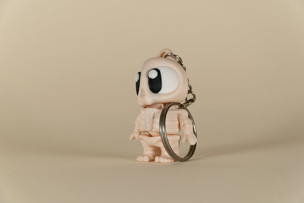 Porte-clés Skeleton articulé MinoZoo beige, noir et blanc, vue trois-quarts avec anneau métallique.